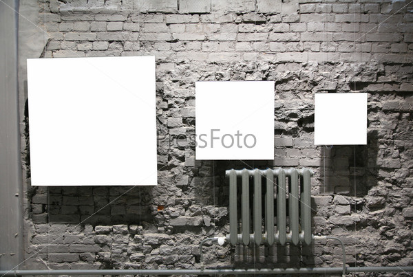 three blank frames on grey brick wall