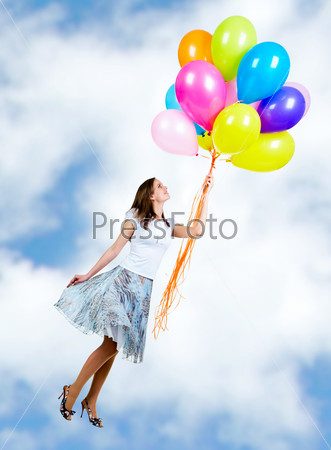 Pretty young woman flying on colorful balloons in the sky