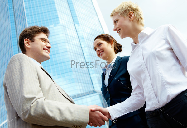 Photo of successful associates handshaking after striking deal outdoors at meeting