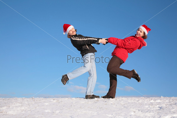 couple dance on  snow hill in santa claus hats 2