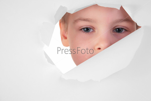 boy looks in a hole in a sheet of a paper