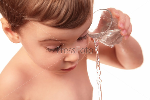 Little child pours out water from glass