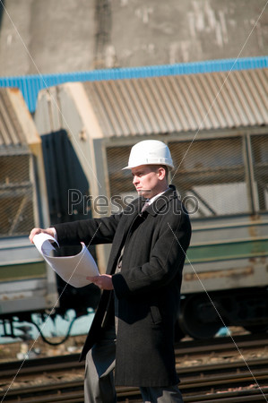 Engineer with white hard hat holding drawing near train