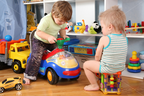 two children in playroom with toy scooter