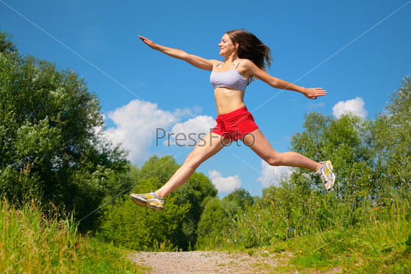 Young woman jumping doing exercise in park