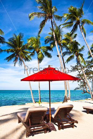 Red umbrella and chairs on sand beach in tropic. Thailand, Koh Chang, Klong Prao beach