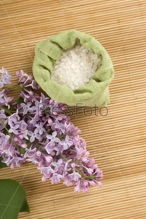 Branch of lilac and green bag with scattered sea salt