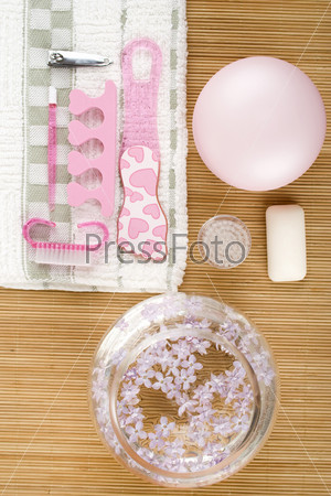 On the wooden table flowers, cream, soap, a brush for cleaning the face and pink pedicure set