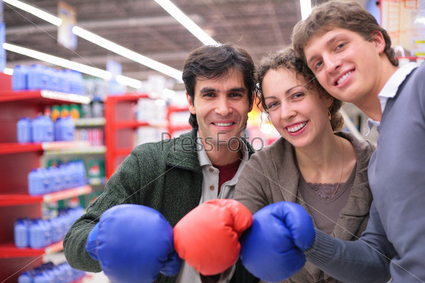 Three friends in boxing gloves in shop