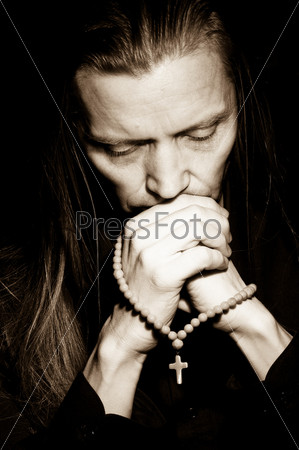 Head and hands of praying man, low-key portrait
