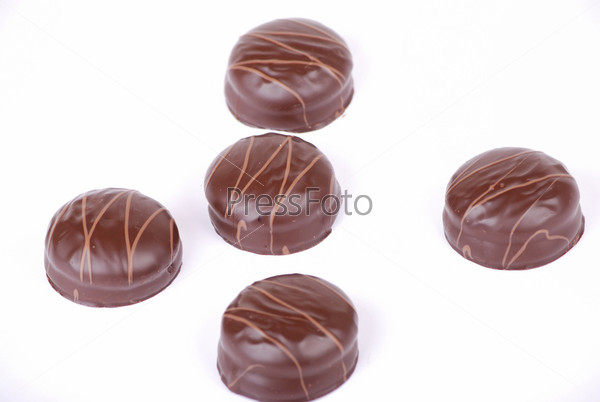 Small chocolate cakes covered with a layer of black chocolate and decorated with a pattern from a milk chocolate.
