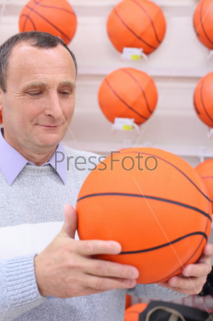 elderly man in shop with basketball ball in hands