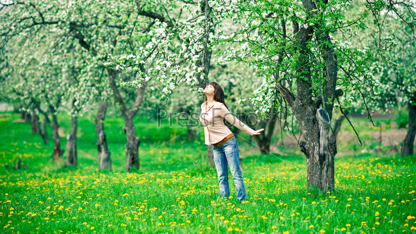 Young woman smelling apple flowers in the garden
