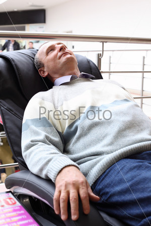 elderly man lies in massage armchair