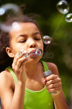 Portrait of cute girl blowing soap bubbles