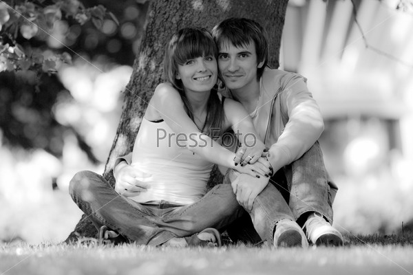 Happy young couple sitting in a  park. Black and white photo