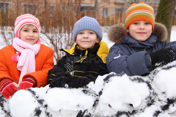 Three children on wall of snow fortress in court yard