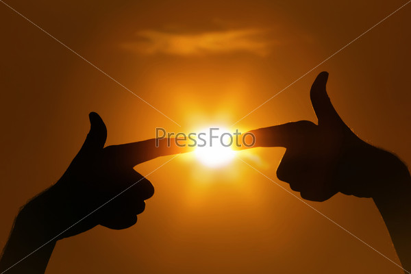 Пальцы, указывающие на заходящее солнце