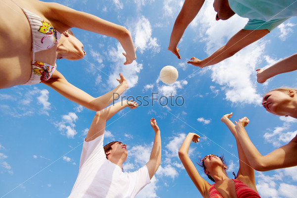 Below view of teenage friends catching ball on background of cloudy sky