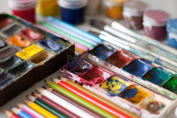 Items for drawing and art: watercolor paint, brushes, colored pencils.