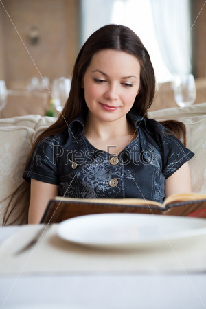 Young woman in restaurant is reading menu