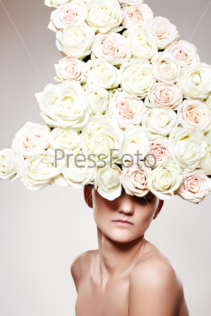 Luxury portrait of young woman model with a big white rose hat in a fashion model pose. Creative wedding accessories, headwear, flowers. Bride looking.