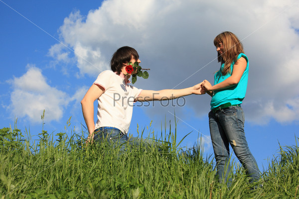 guy with rose in mouth and girl in grass
