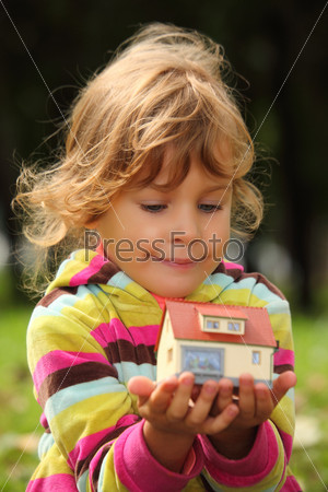 little girl with toy small house in hands outdoor