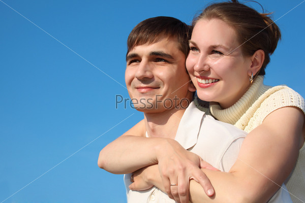 woman embraces  man from behind on sky