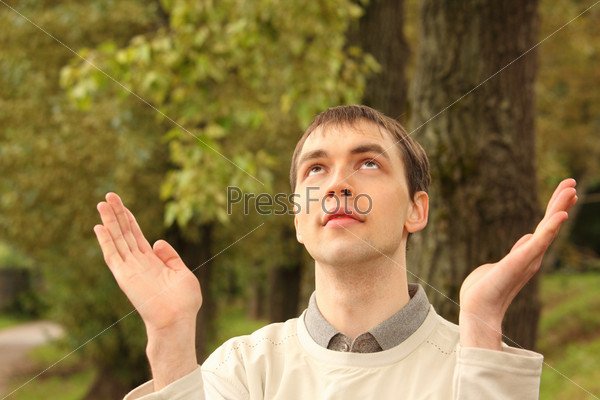 young man prays outdoor in summer