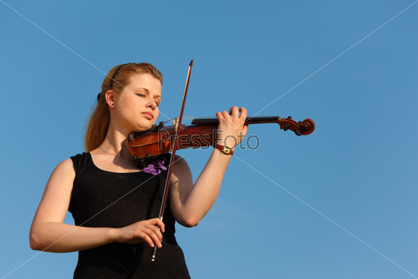 Girl plays violin against sky