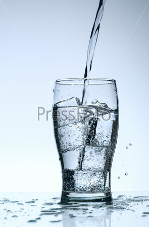 Cold purified water in the glass with bubbles and reflection on the wet background