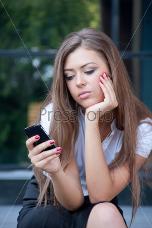 young woman looks in a cellular telephone and longs having seen something on the screen. Business style