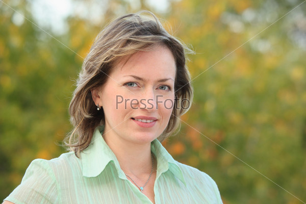 portrait of woman in early fall park. she is looking at camera