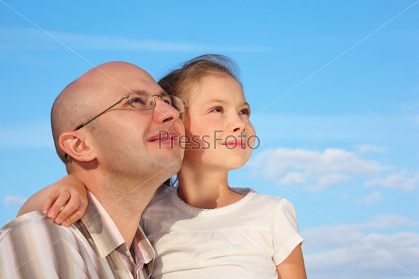 father and little girl on sky background are looking at sky