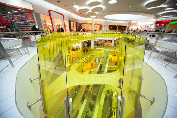 Escalator, stores, cafe, snack-bar and many buyers and customers in shopping center
