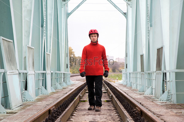 man worker blindly in a helmet stands on the rails bridge