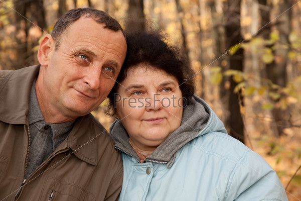 Old man and old woman walk in autumnal forest