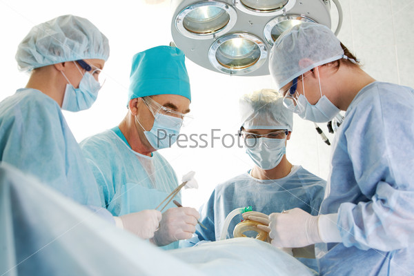 Several surgeons surrounding patient on operation table during their work