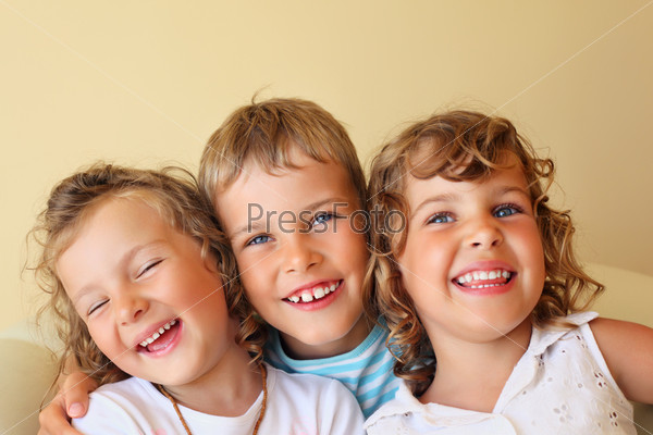 Smiling children three together in cozy, girl at left closed eyes
