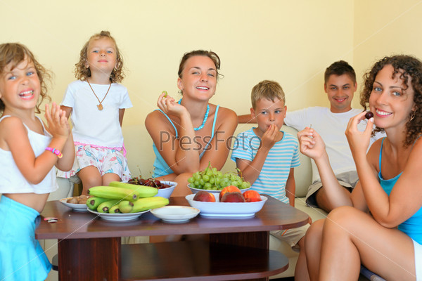 big happy family with children eats fruit in cozy room