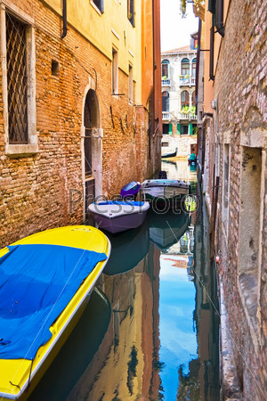 narrow canal with boats in Venice, Italy