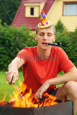 young man with calumet near brazier on picnic, happy birthday party