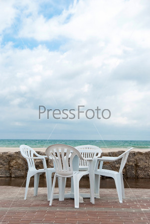 Empty table and four chairs in the beach near sea