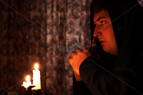Человек молится при свечах