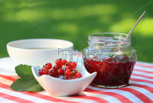 Jar of red currant jam and tea in the garden