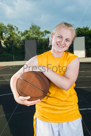 Teenage girl with basketball at streetball playground smiling