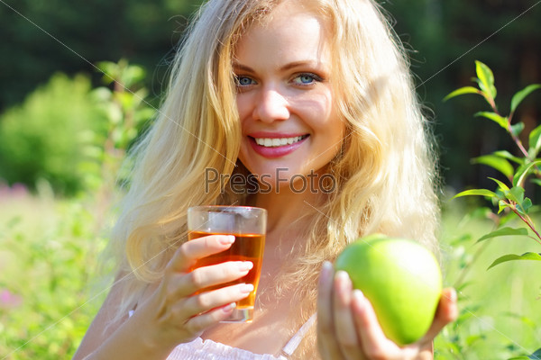 Beautiful girl is holding an apple and juice