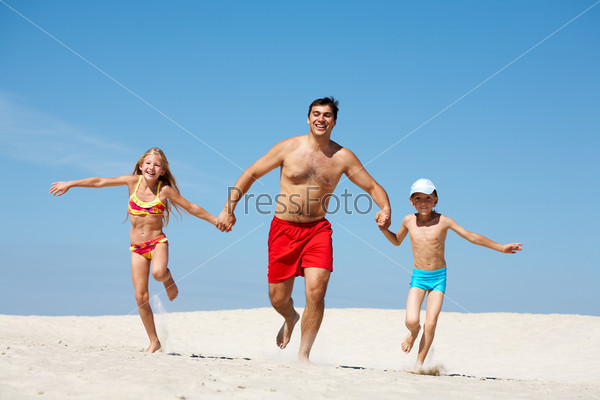 Photo of happy family running down sand on summer vacation