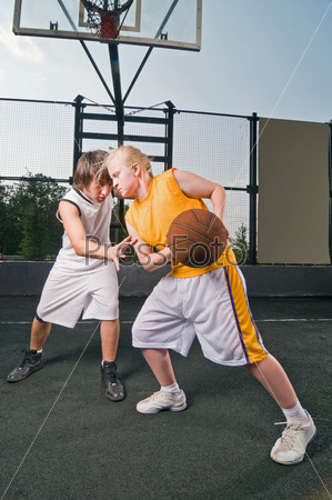 Teenage boy and girl playing basketball at the street playground
